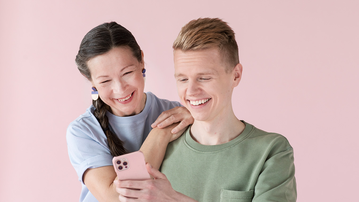 Nainen ja nuori mies katsovat yhdessä kännykän ruutua.